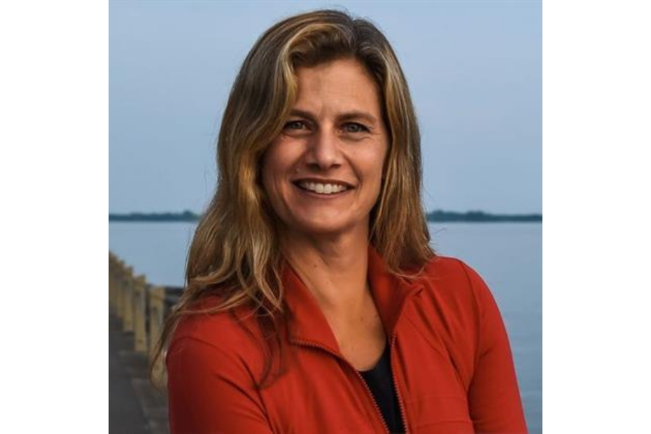 Kathy Doering smiles as she stands in front of a river